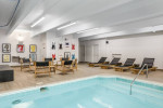 Indoor swimming pool area at Independence Green Apartments with lounge chairs and modern decor.