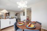 Cozy dining area with a table set for guests, featuring stylish decor and warm lighting in an apartment.