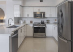 Modern kitchen with stainless steel appliances and sleek white cabinetry in luxury apartment.