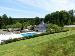 View of the pool and clubhouse at The Park at Salisbury Apartments, surrounded by green landscaping and trees.