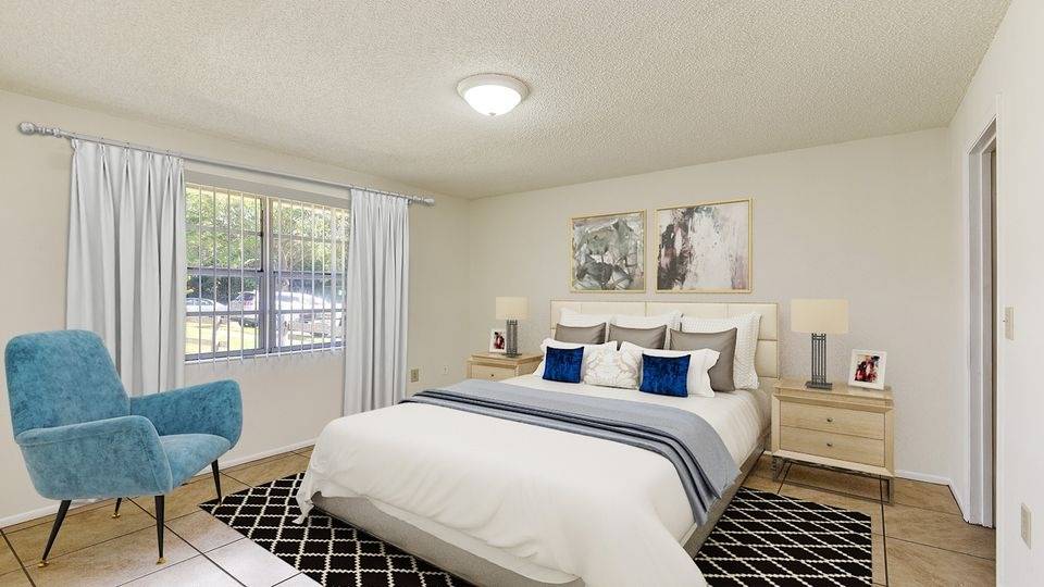 Spacious bedroom with blue chair and elegant decor in Kissimmee apartment.