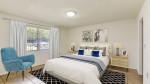 Spacious bedroom with blue chair and elegant decor in Kissimmee apartment.