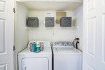 In-unit washer and dryer in a modern apartment laundry area with shelving and storage boxes