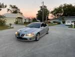 2004 Supercharged GTO in silver parked on a residential street, showcasing its sporty design and power features.