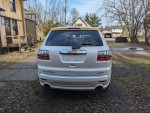 Rear view of a 2012 GMC Acadia Denali with premium wheels and dual sun roofs parked in a residential area.