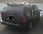 2000 Dodge Caravan with roof rack and hitch, showing signs of wear and tear, parked outdoors.