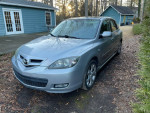 2007 Mazda 3 i Sport FWD hatchback parked in a driveway with visible wear and tear