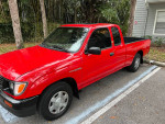 1995 Toyota Tacoma Xtra cab in red, showcasing original condition, parked in a residential area.