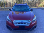 Front view of a low mileage 2016 Subaru Outback in red, showcasing its sleek design and all-wheel drive features.