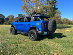 2022 Ford Bronco Big Bend 4WD with new tires and lift, parked in a grassy field on a sunny day.