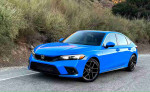 2024 Honda Civic Sport hatchback in blue color parked on a scenic road surrounded by greenery.