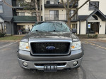 Front view of a 2007 Ford F-150 XLT 4WD pickup truck parked outside, highlighting its sleek design and grill.