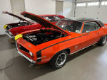 1969 Chevrolet Camaro SS in Hugger orange with black stripes, showcasing its engine and interior.