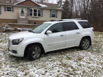 2016 GMC Acadia Denali FWD parked on grass with light snow, showcasing its exterior and sleek design.