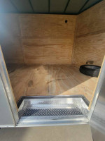 Interior view of a 2024 24 ft enclosed box trailer with wood flooring and a spare tire