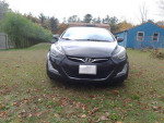 Front view of a 2015 Hyundai Elantra SE in excellent condition, parked in a grassy area with autumn leaves.