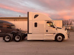 Side view of a white 2018 Freightliner Cascadia CA126 truck during sunset, showcasing its clean design.