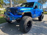 Blue Jeep Rubicon 392 with lifted suspension and oversized tires, parked in a driveway.