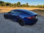 2017 Tesla Model S 75 in blue metallic color, parked on gravel with panoramic roof and black wheels.