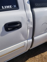 Close-up of the damaged door of a 2003 Chevrolet 1500HD truck for sale with salvage title.