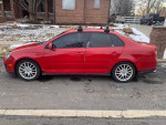 Red Volkswagen Jetta GLI parked, showing body details and snow tires for winter performance.
