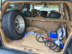 Interior of a 1997 Jeep Cherokee with a spare tire and tools in the cargo area