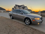 Silver Nissan Maxima SE parked on driveway at sunset, showcasing its sleek design and good condition.