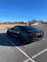 2010 Chevrolet Camaro RS in black with tinted windows parked in a lot, showcasing sporty design and modern features.