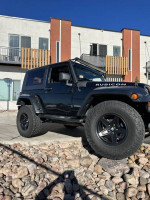 2007 Jeep Wrangler Rubicon in black parked on a rocky surface with visible upgrades and 35-inch tires.
