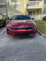 Front view of a red 2023 Kia K5 GT parked outside, showcasing its sporty design and low mileage.