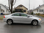 2009 Volvo S80 T6 AWD in silver, showcasing sleek design, parked in residential area on a rainy day.
