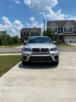 Front view of a 2012 BMW X5 in great condition parked in a residential area with clear blue skies.