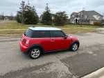 2013 Mini Cooper in red parked on a street, showcasing its sleek design and compact size.
