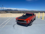 1970 Ford Mustang Mach 1 in Calypso Coral color parked with mountains in the background.