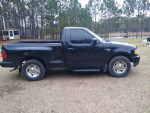 1998 Ford F-150 XLT 4WD black truck parked in a grassy area, good condition with visible details.