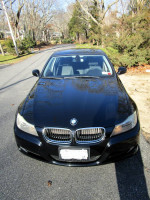 Front view of a black 2011 BMW 328i X Drive parked on a tree-lined street.