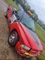 1999 Dodge Dakota truck with 136,000 miles, showing visible scratches and a dependable build, parked outdoors.