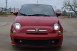 Front view of a red 2015 FIAT 500 Abarth with headlights on, showcasing sporty design.