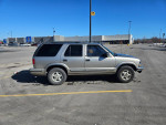 1999 Chevrolet Blazer parked at Walmart, showing its side profile and LED headlights.