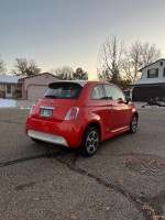 Red 2014 FIAT 500e parked on a residential street, showcasing its compact design and electric vehicle features.