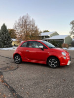2014 red FIAT 500e parked on a street, showcasing its compact electric design and smooth lines.
