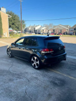 Black Volkswagen Jetta GTI parked, showcasing sporty alloy wheels and a clean exterior on a sunny day.