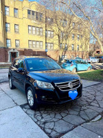 2009 Volkswagen Tiguan SE 4Motion SUV parked in front of an apartment building, showcasing its sleek black design.
