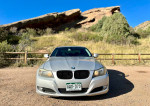 Front view of a 2011 BMW 328i parked in a scenic outdoor location with grass and rocks.