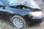 Damaged 2014 Chrysler 200 Touring FWD with a slightly open hood, located on a grassy area.