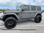 2019 Jeep Wrangler Unlimited Moab 4WD in gray with custom features, parked in a lot.