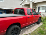2008 Dodge RAM 1500 Big Horn edition in red, parked outside with a bed cover and dark tinted windows.