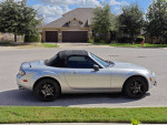 2006 Mazda MX5 Miata in silver, parked on street, showcasing its stylish design and low mileage.