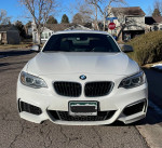 Front view of a white 2015 BMW M235i coupe with a sporty design and custom exhaust.