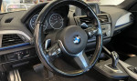 Interior view of a 2015 BMW M235i coupe showcasing a stylish dashboard and steering wheel.